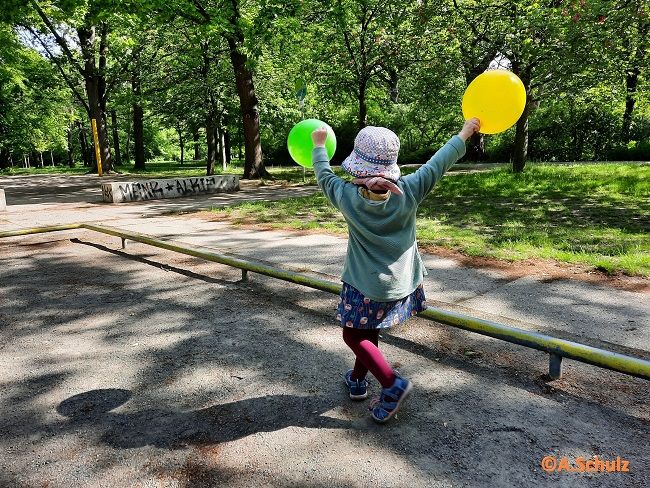 zur Vergrößerungsansicht des Bildes: Kind spielt mit zwei Luftballons im Park