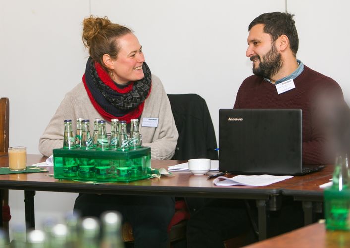 Zwei Promovierende an einem Tisch unterhalten sich lachend