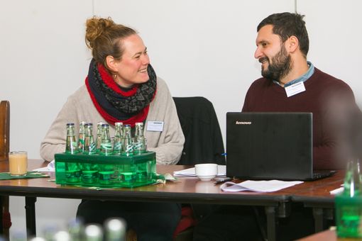 Two doctoral researchers at a table have a laughing conversation