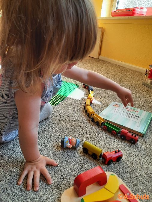 enlarge the image: Child sits on the floor and plays with a wooden train