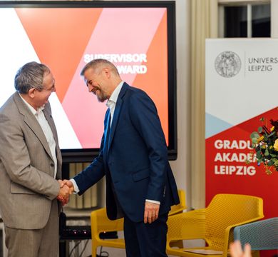 Verleihung des Supervisor Awards an Prof. Dr. Holger Kohlmann Prof. Gläser gratuliert Prof. Kohlmann, ein Blumenstrauß wird gereicht